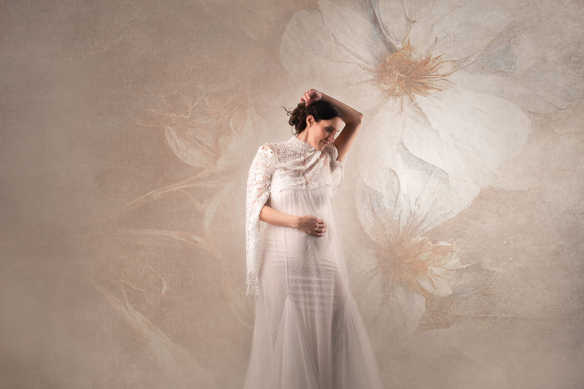 Babybauchfoto im Studio im weißen Kleid vor blumigem Hintergrund