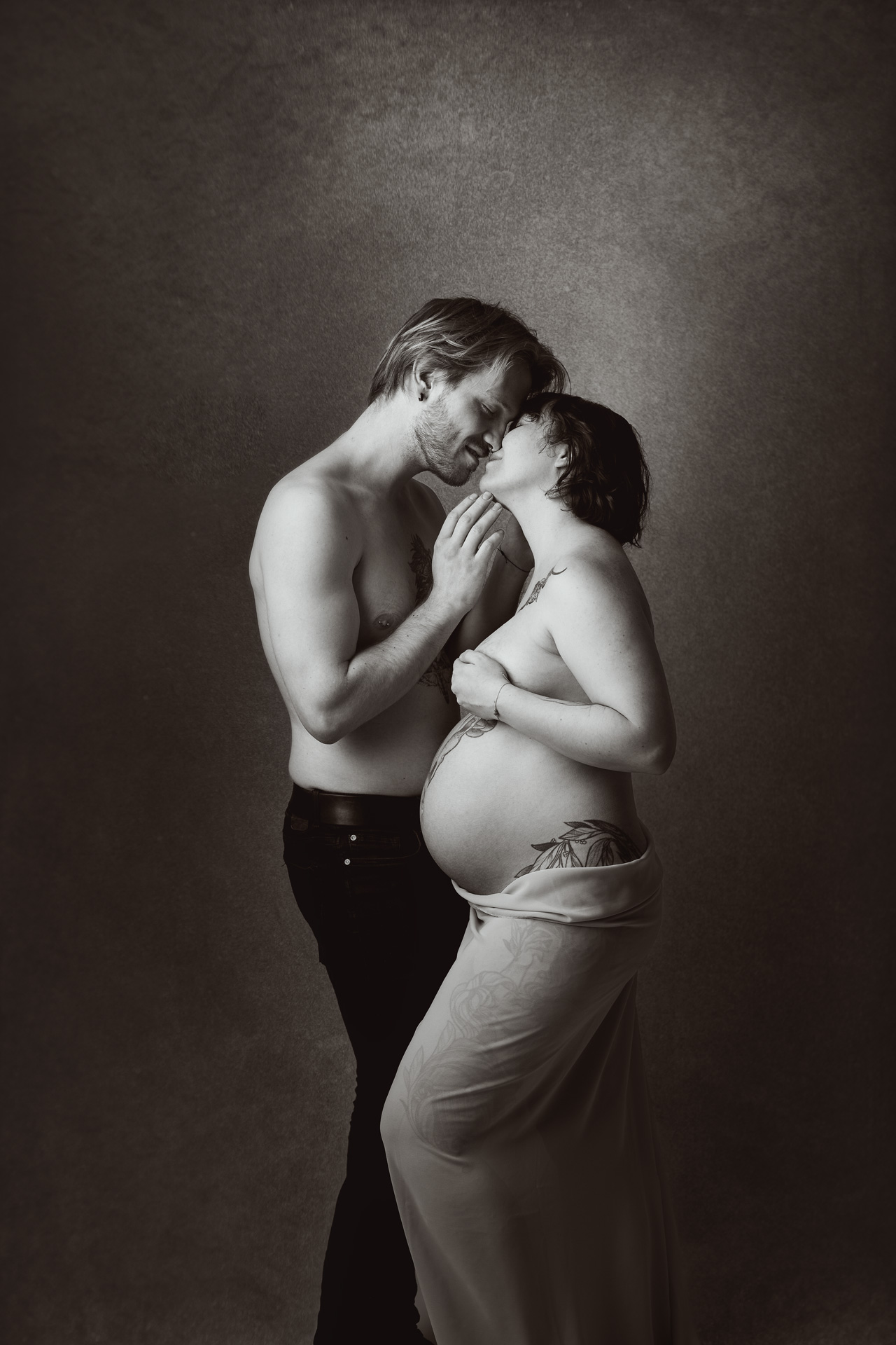 7Aktshooting schwangere Frau im grauen Kleid und schwarzen Tuch um die Schultern steht im Wald mit einem Hund