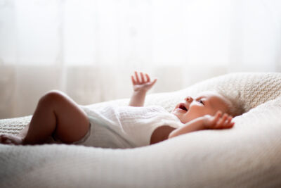 Lachendes Baby liegt auf einer weißen Decke