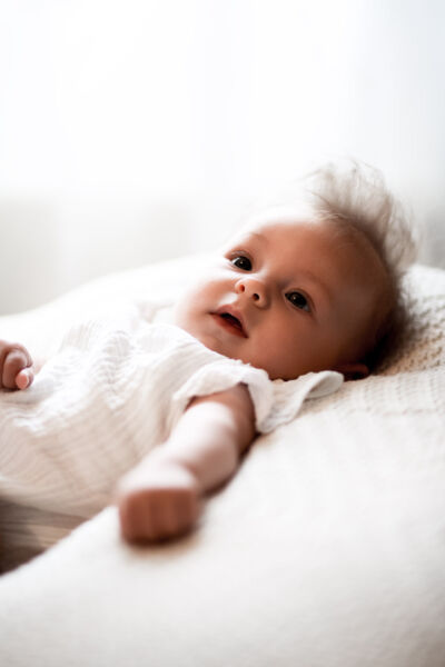 Baby mit langem Haar auf weißer Decke